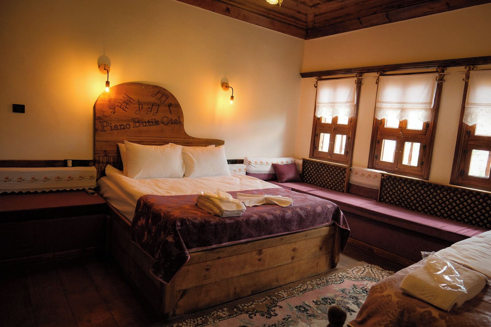 Una cama de madera tradicional con cabecera, un banco al lado y una ventana con contraventanas.