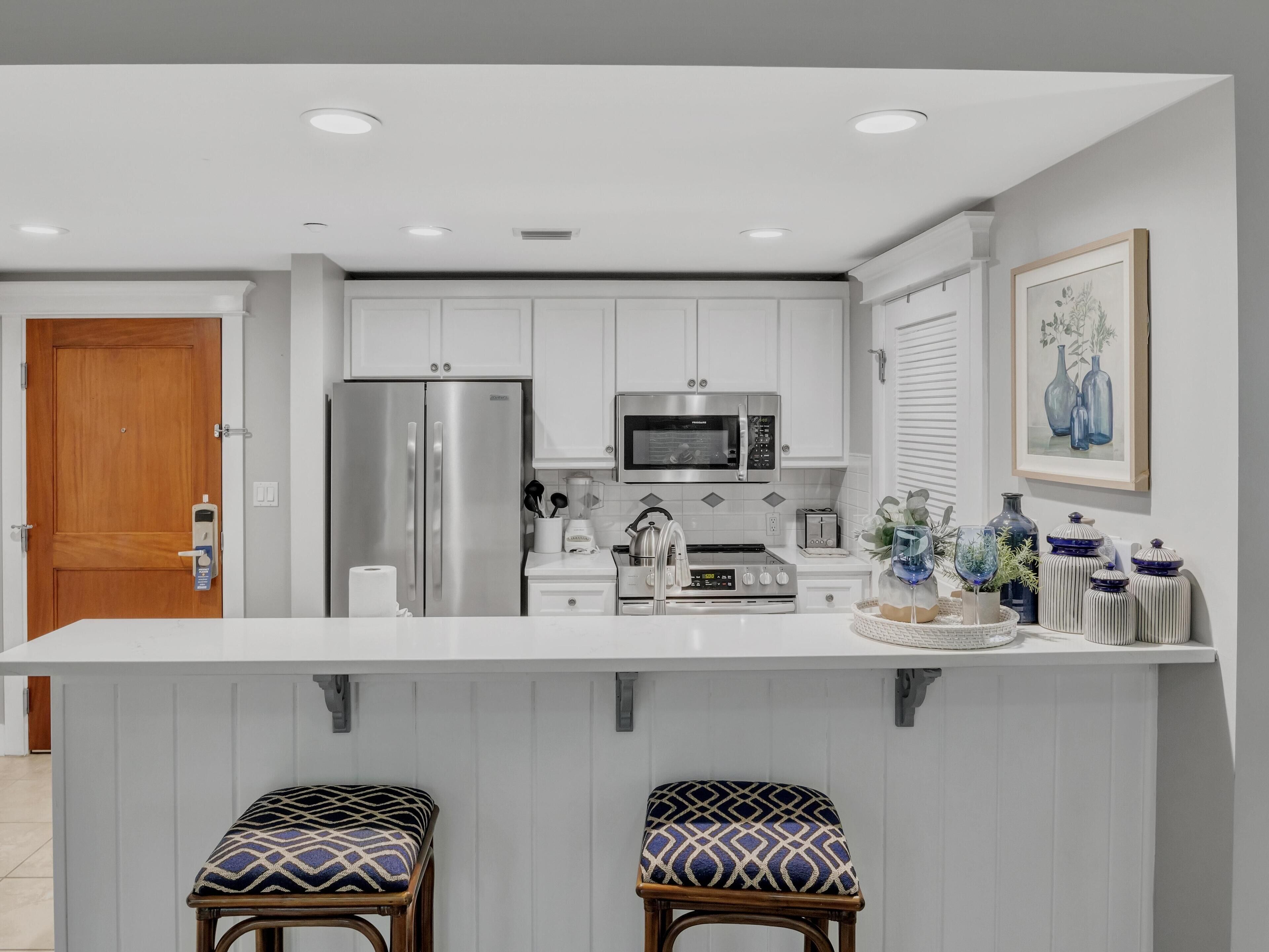 A modern kitchen with white cabinets, stainless steel appliances, and a central island with stools.