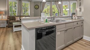 A modern kitchen with a dishwasher, double sink, and a dining area with a sofa.