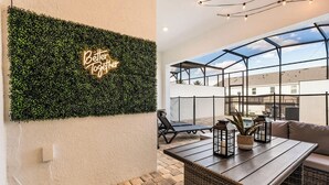 Une terrasse sur le toit agrémentée d’un mur végétal, d’une pancarte portant l’inscription « Mieux ensemble », de fauteuils confortables, d’une table avec des plantes en pot et d’une vue sur les bâtiments à travers une paroi de verre.