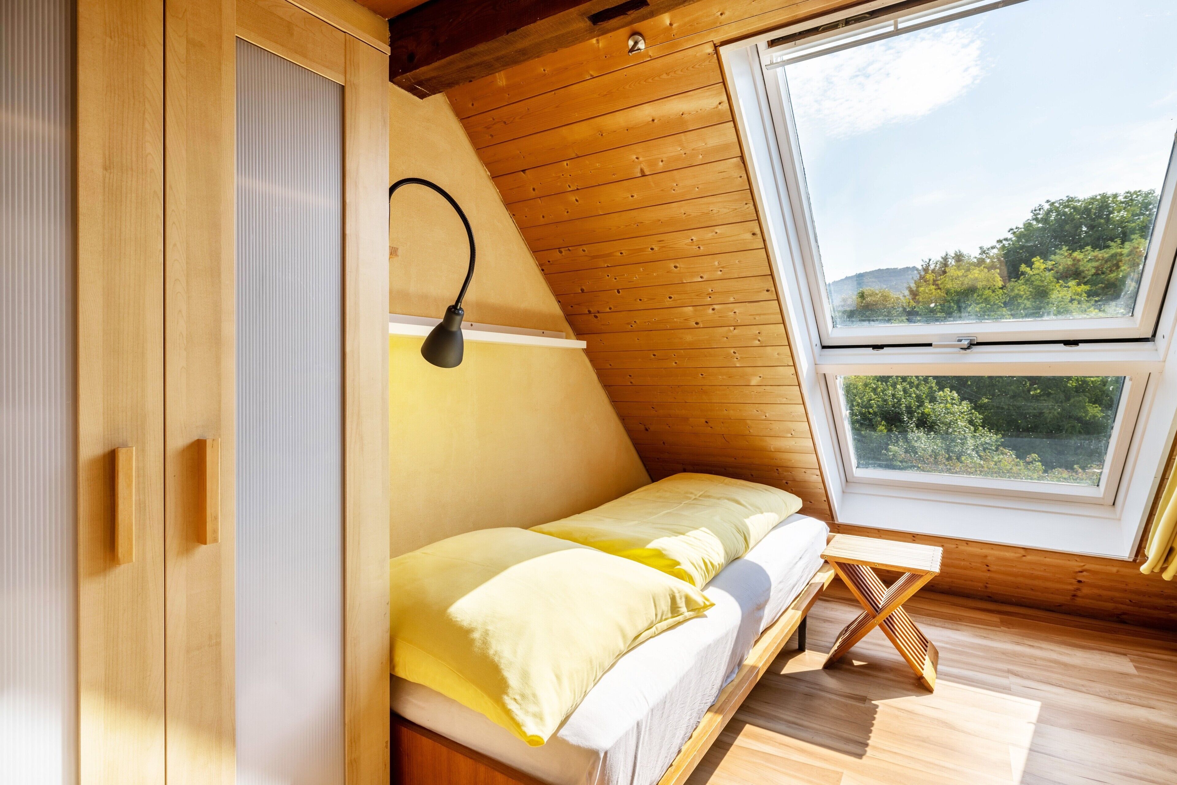 A wooden room with a bed, a window, and a lamp.