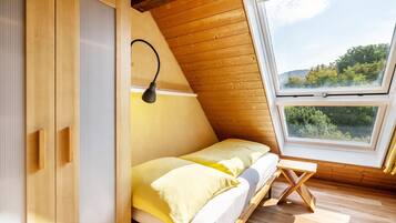 A wooden room with a bed, a window, and a lamp.