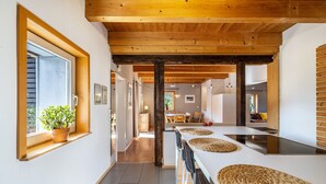 Eine moderne Küche mit Holzboden, einem großen Fenster mit Pflanze und einer zentralen Kochinsel mit gewebten Platzsets.