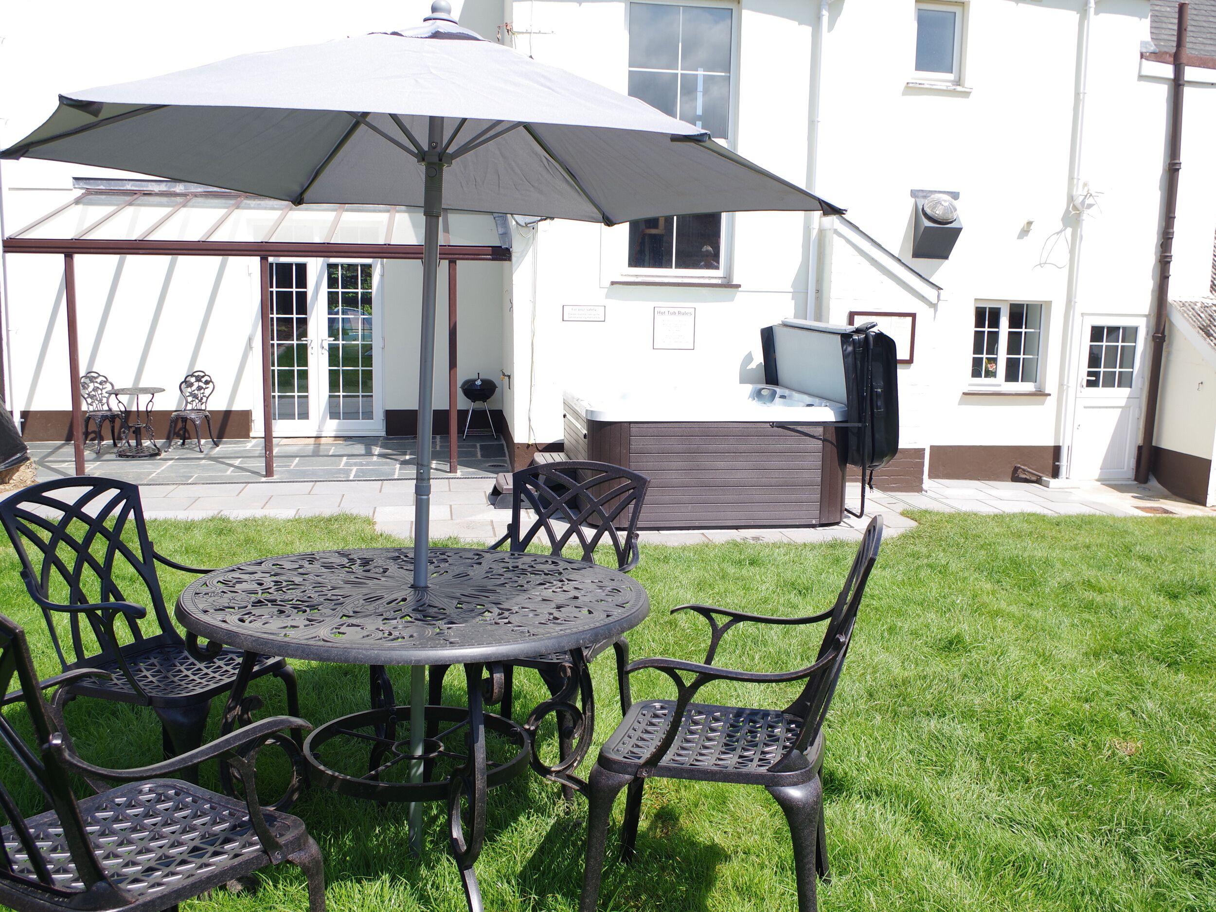 A patio area with a round table, four chairs, and a large umbrella.