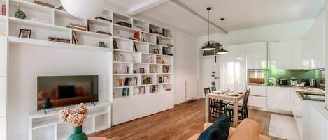 A modern living room with a TV, bookshelves, a sofa, and a dining area.
