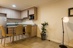 A modern kitchen with wooden cabinets, a built-in microwave, a sink, and a dining area with two chairs.