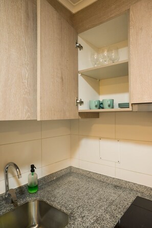 Une cuisine dotée d’un plan de travail en granit, d’un évier en acier inoxydable et d’un meuble avec un porte-verres à vin.