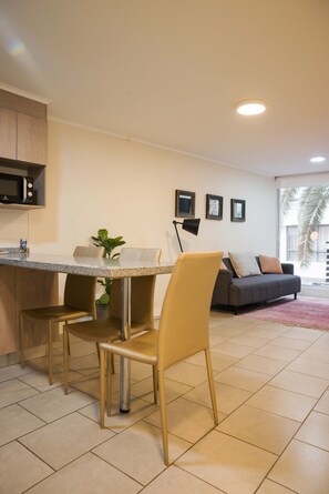 A modern kitchen with a dining table and chairs, a microwave, and a plant. - Central 1BR1BA in Santiago Balcony & Nearby Metro (Unknown)