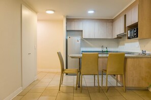 Une cuisine dotée d’un îlot central intégré, de deux chaises, d’un réfrigérateur et d’armoires en bois.