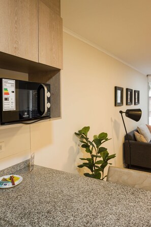 A kitchen with a microwave, granite countertop, and a potted plant.