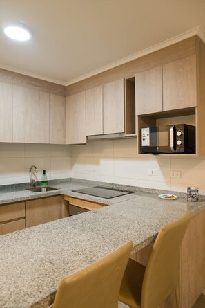 A kitchen with granite countertops, wooden cabinets, a stainless steel sink, and a microwave. - Central 1BR1BA in Santiago Balcony & Nearby Metro (Unknown)