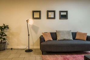 A living room with a grey sofa, two cushions, a floor lamp, and three wall-mounted mirrors. - Central 1BR1BA in Santiago Balcony & Nearby Metro (Unknown)