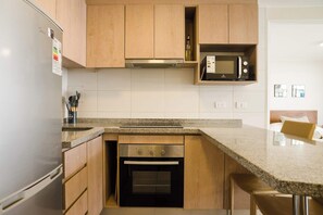 A kitchen with wooden cabinets, a stainless steel refrigerator, a built-in microwave, and a double oven. - Metro-Accessible Apartment with Terrace | Santiago (Santiago)