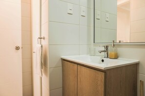 A bathroom with a white sink, wooden cabinet, and a mirror above it. - Metro-Accessible Apartment with Terrace Santiago (Santiago)