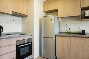 Una cocina con armarios de madera, un refrigerador de acero inoxidable y un horno empotrado.