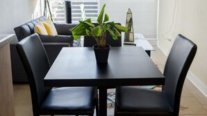 A modern dining area with a black table and chairs, a potted plant, and a sofa with cushions. - Chic 1BR Oasis in Centro Metro Bliss Your Doorstep (Santiago)