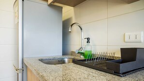 A kitchen with a stainless steel sink, a faucet, a soap dispenser, and a black tray. - Chic 1BR Oasis in Centro Metro Bliss Your Doorstep (Santiago)