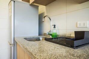 Una cocina con un lavamanos de acero inoxidable, un grifo, dispensador de jabón y una bandeja negra.
