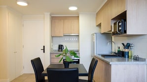 A modern kitchen with a dining area, featuring a black table, chairs, a potted plant, and a microwave. - Chic 1BR Oasis in Centro Metro Bliss Your Doorstep (Santiago)