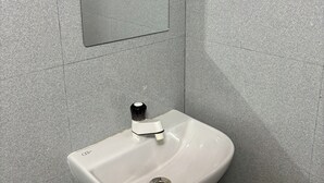 A bathroom with a white sink, a mirror, and a tiled wall.