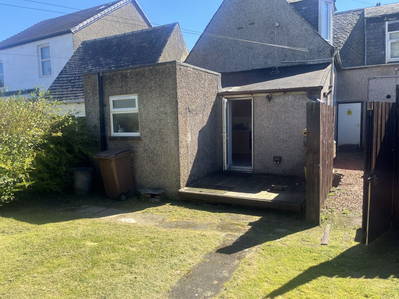 Ein kleines, eingeschossiges Gebäude mit Satteldach, einer Tür, die zu einer Veranda führt, und einem sichtbaren Fenster.