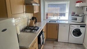 A kitchen with a stove, sink, microwave, and washing machine.
