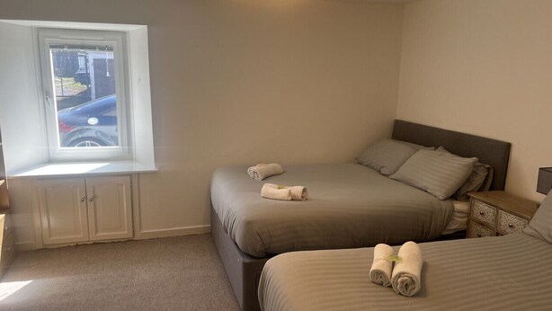 A bedroom with two beds, a window, and a nightstand.