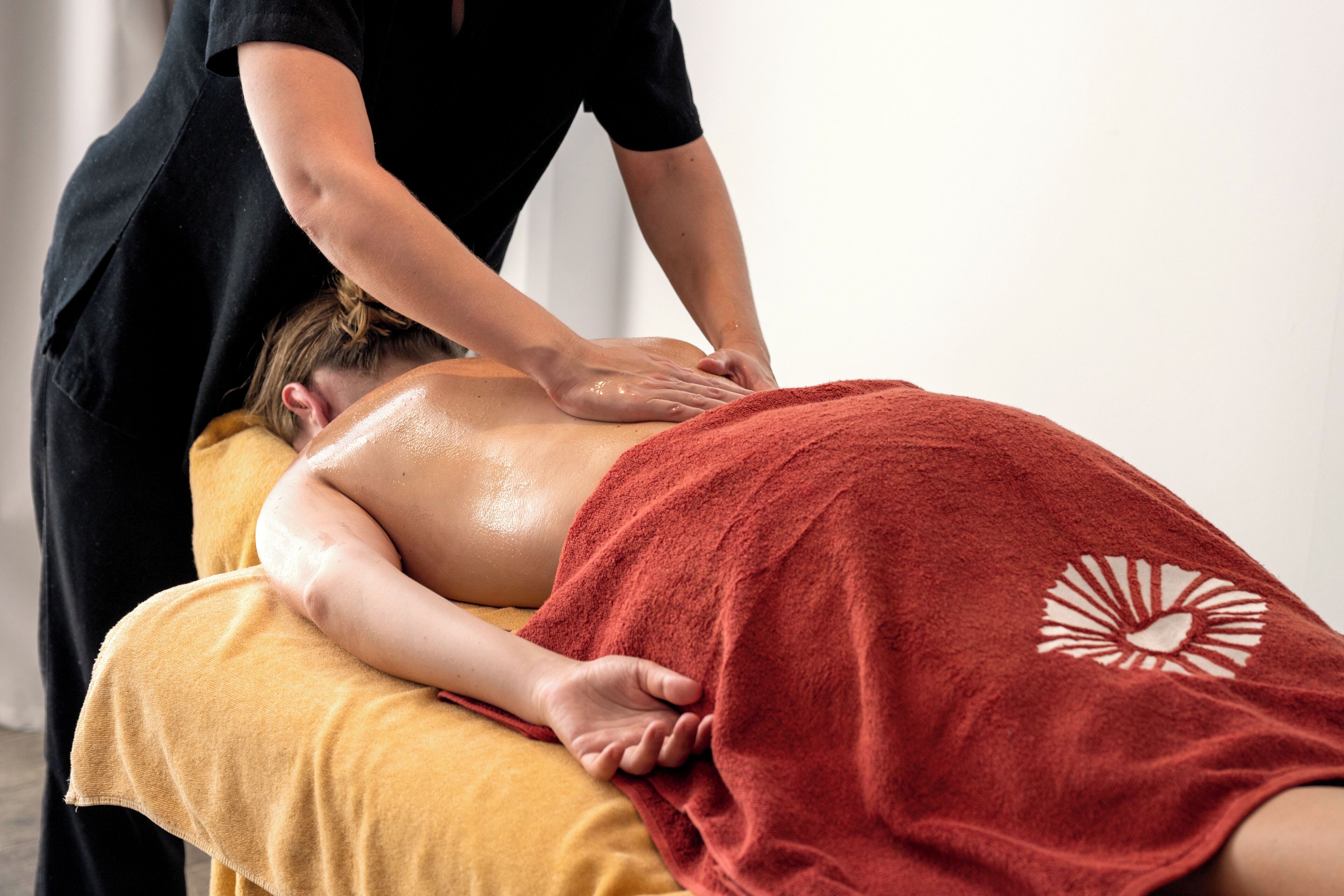 A person receiving a back massage on a massage table with a towel covering their lower body.