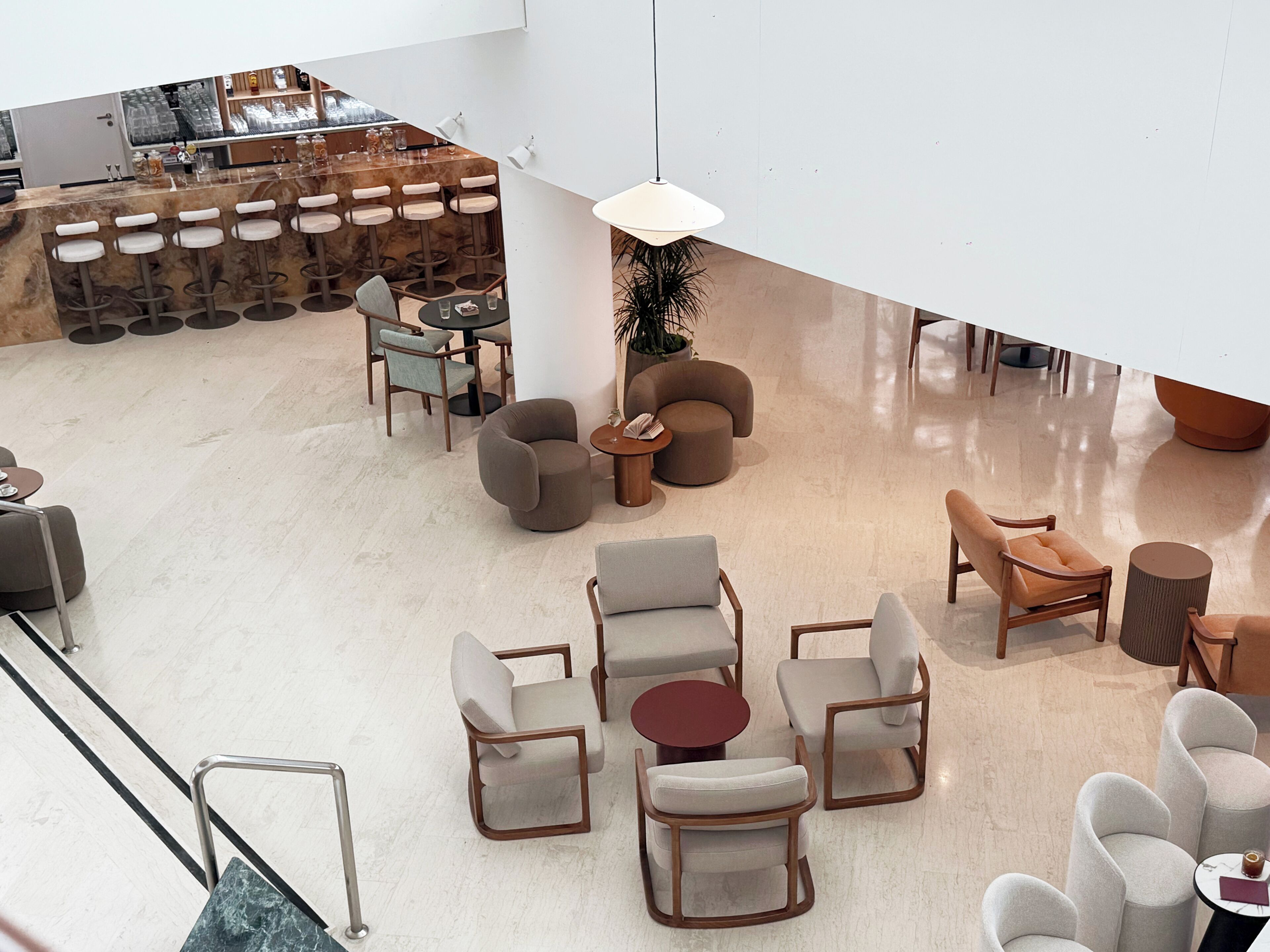 A modern lounge area with a bar, seating arrangements, and a staircase.