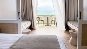 Une chambre d’hôtel avec un lit, une petite table, deux chaises et une vue sur la mer.