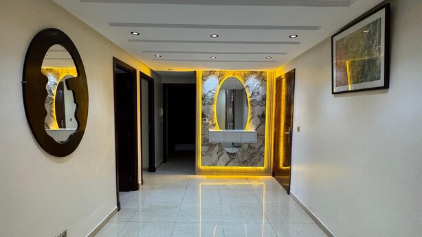 A modern hotel lobby with a marble reception desk, a large mirror, recessed lighting, and a framed artwork on the wall. - Sweat home Pool (Agadir)
