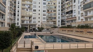 A multi-story residential building with balconies, a swimming pool, and a staircase leading to the upper floors. - Sweat home Pool (Agadir)