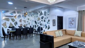 Una sala de estar moderna con sofá, comedor y paneles decorativos en la pared.