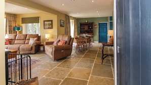 A spacious living area with a brown leather sofa, a dining table with chairs, and a kitchen area visible through an open door. - Dingle (Kidderminster)