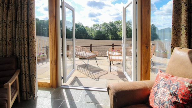 A room with a sliding glass door leading to an outdoor patio with wicker furniture and a view of a field. - Dingle (Kidderminster)