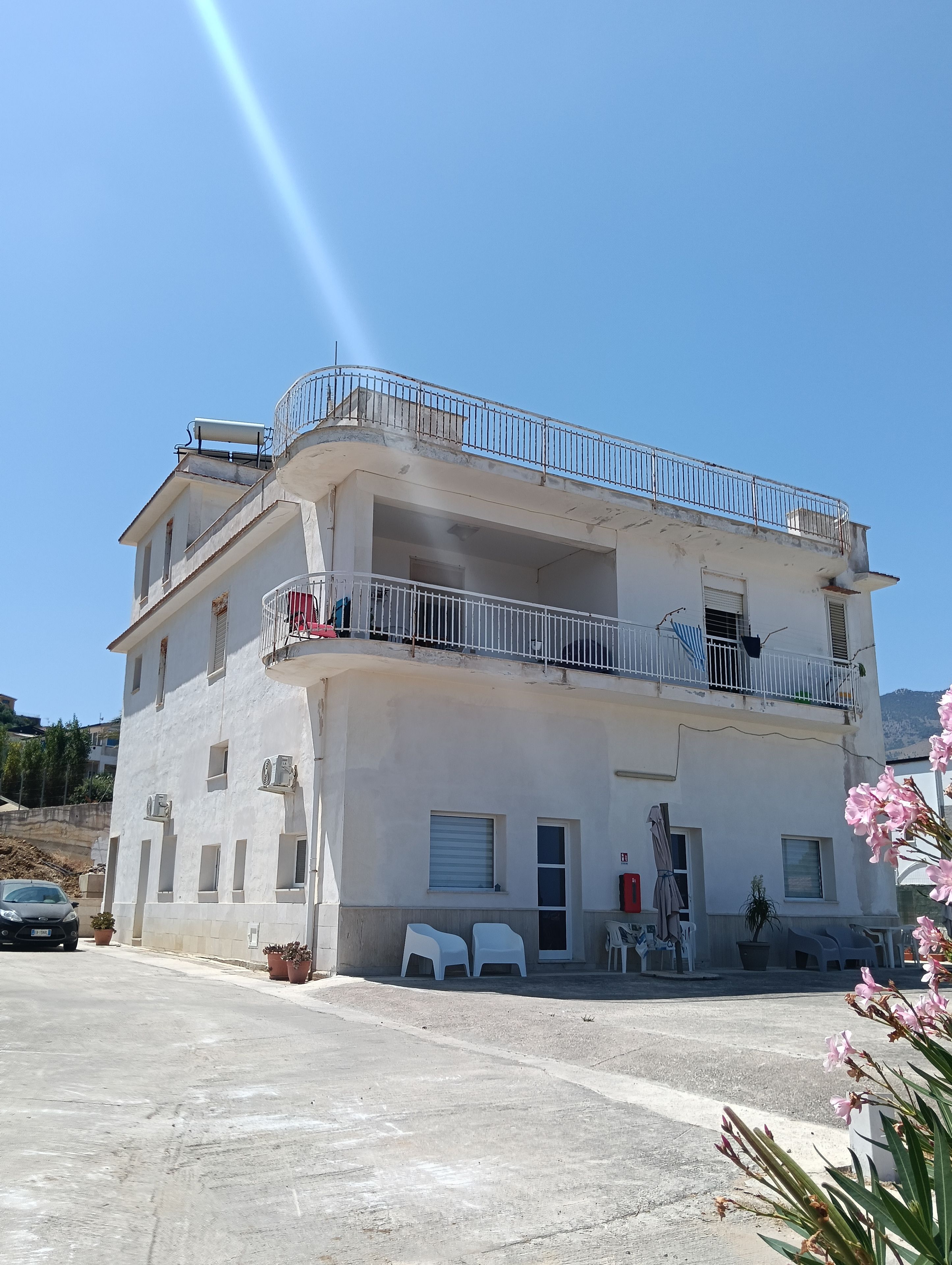 Un edificio a due piani con balconi, condizionatori e un'area di parcheggio.