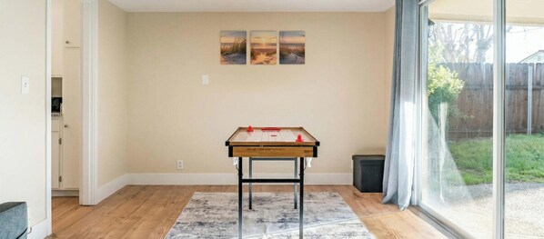 A room with a wooden table, a rug, and a window with a view of a backyard. - Family, Pet & Long Vacation Friendly, Fenced Yard (Sacramento)