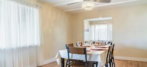 A dining area with a table set for four, a ceiling fan, and a chandelier. - Family, Pet & Long Vacation Friendly, Fenced Yard (Sacramento)