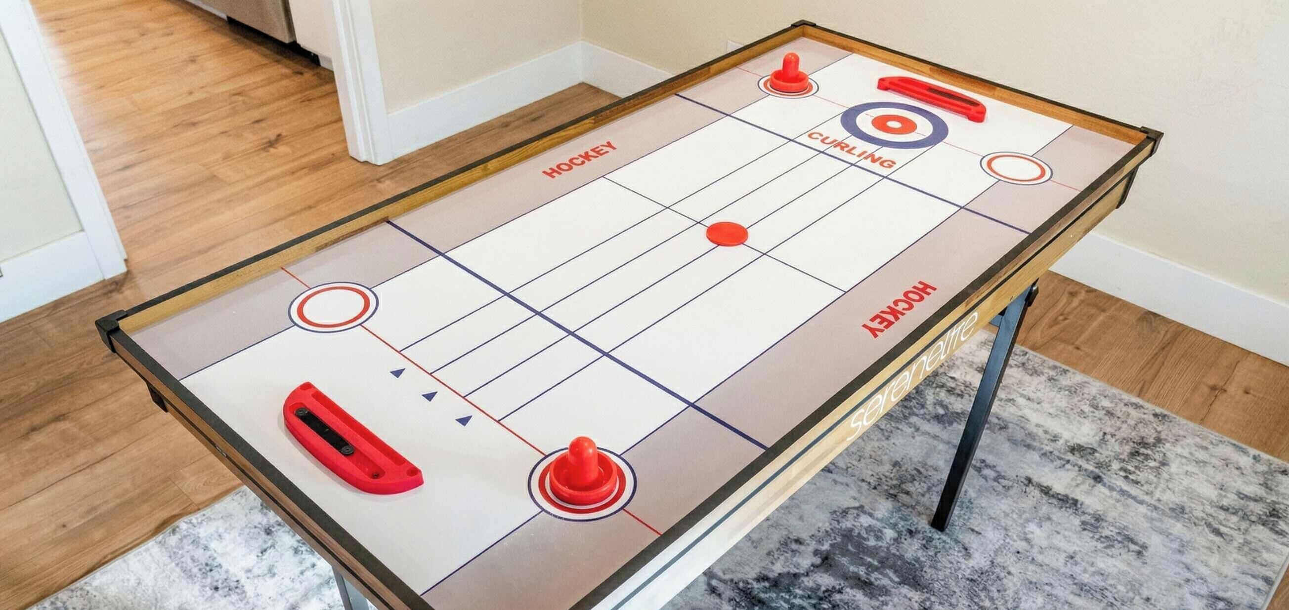 Ein Tischhockey-Spiel mit Holztisch, roten und blauen Pucken und einer Zielscheibe auf dem Tisch.
