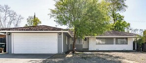 A two-story house with a garage, a front porch, and a tree in front. - Family, Pet & Long Vacation Friendly, Fenced Yard (Sacramento)