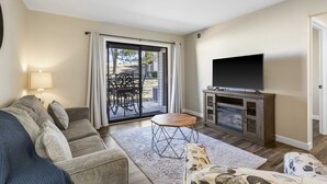 A living room with a sofa, a coffee table, a TV, and a sliding glass door leading to an outdoor area. - Fairway View Duo Stay for 12! (Branson)