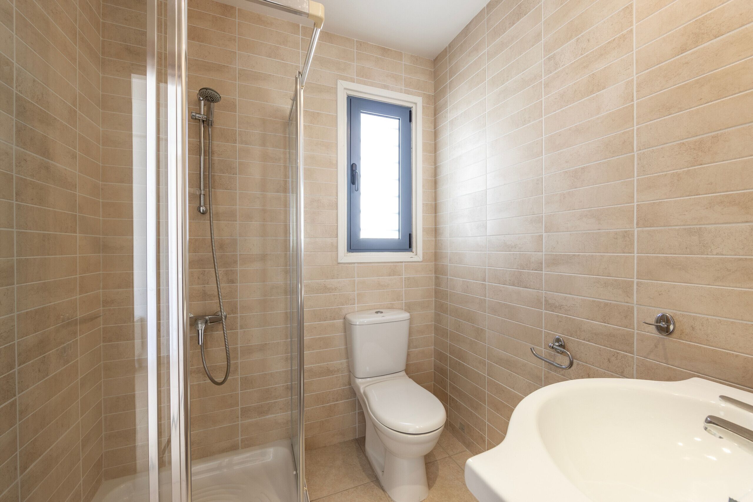 A bathroom with a glass shower enclosure, a toilet, and a bathtub.