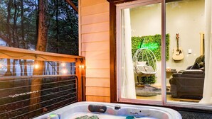Un jacuzzi con vista a un patio, una silla colgante y una guitarra.