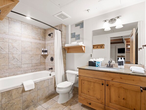 A modern bathroom with a bathtub, toilet, and vanity. - Newpark 315-B | Food Galley | Mountain & Preserve Views | Fireplace | Hot Tub & Pool | Walk to Shops (Park City)