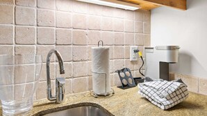 A kitchen with a granite countertop, stainless steel sink, and a built-in oven.