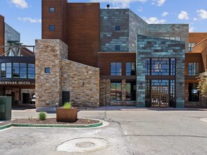 Un hotel moderno con fachada de piedra y amplios ventanales.