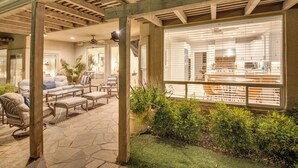 An outdoor patio area with stone flooring, wooden pergola, and seating arrangements.