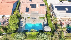 An aerial view of a residential property with a swimming pool, solar panels, and a well-maintained garden.