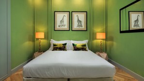 A neatly made bed with white linens and two decorative pillows, flanked by two bedside tables with lamps, in a room with green walls and framed artwork. - ENCHANTING PENTHOUSE 360° Panoramic View in the Heart of Florence. (Firenze)