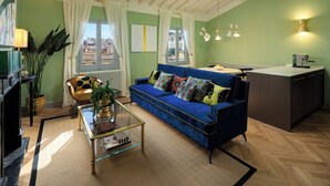 A living room with a blue sofa, a glass coffee table, and a view of the city through a window. - ENCHANTING PENTHOUSE 360° Panoramic View in the Heart of Florence. (Firenze)